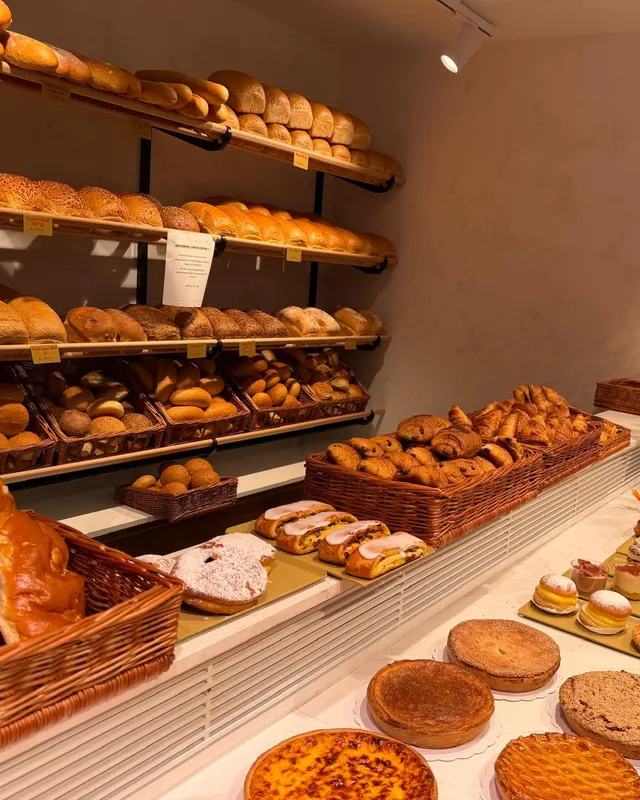 Onze bakkerijhoek met rekken vers brood, manden koffiekoeken en een toog vol taarten