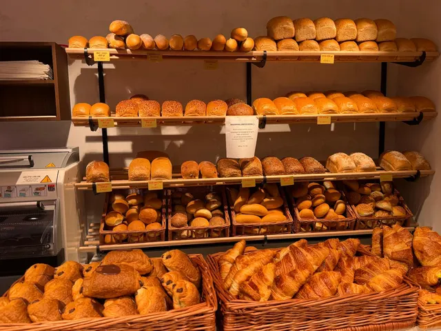 Rekken met vers brood en pistolets, met manden croissants en chocoladebroodjes vooraan