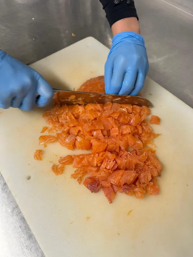 Gerookte zalm wordt met de hand in blokjes gesneden