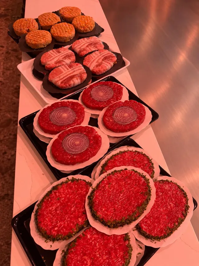 Schalen met huisgemaakte burgers op de toog: gepaneerd, met spek omwikkeld, met een schijf rode ui en met een kruidenrand