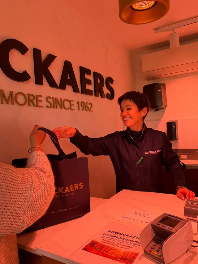 Een klant krijgt de boodschappen in een Bronckaers-tas aangereikt aan de kassa