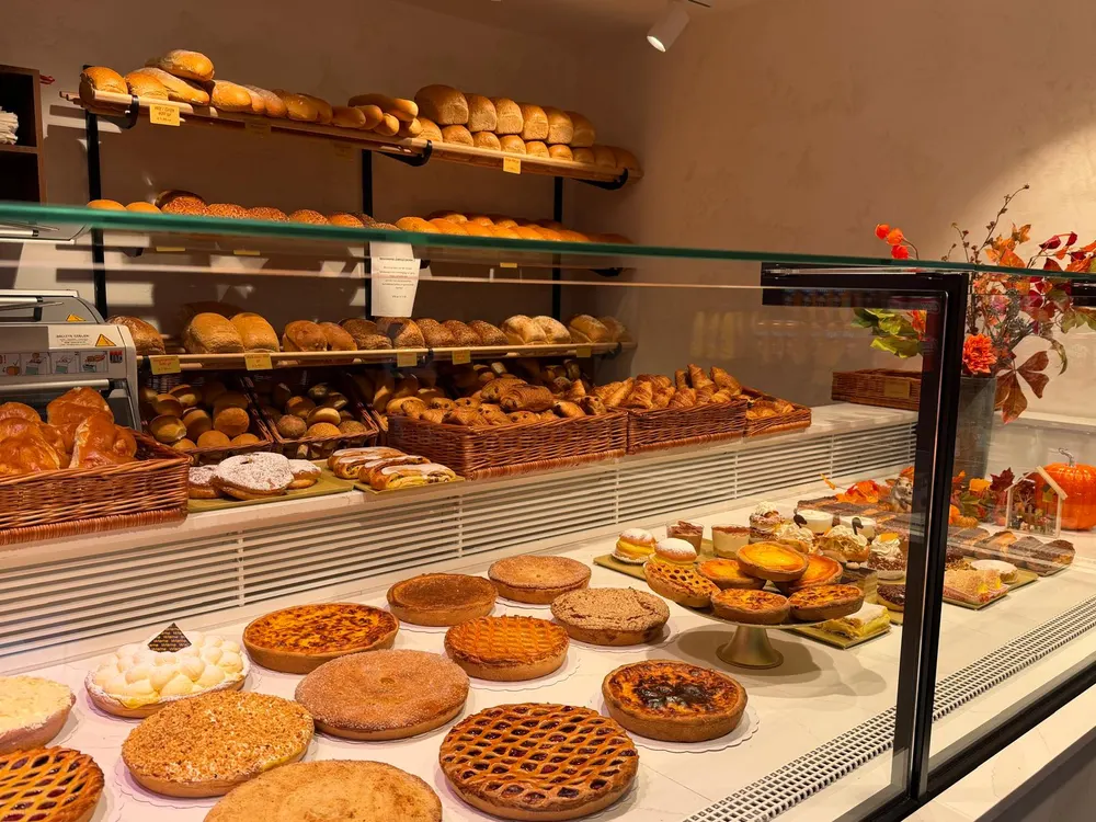 Toog vol taarten, rijsttaartjes en gebak, met rekken brood en koffiekoeken erachter