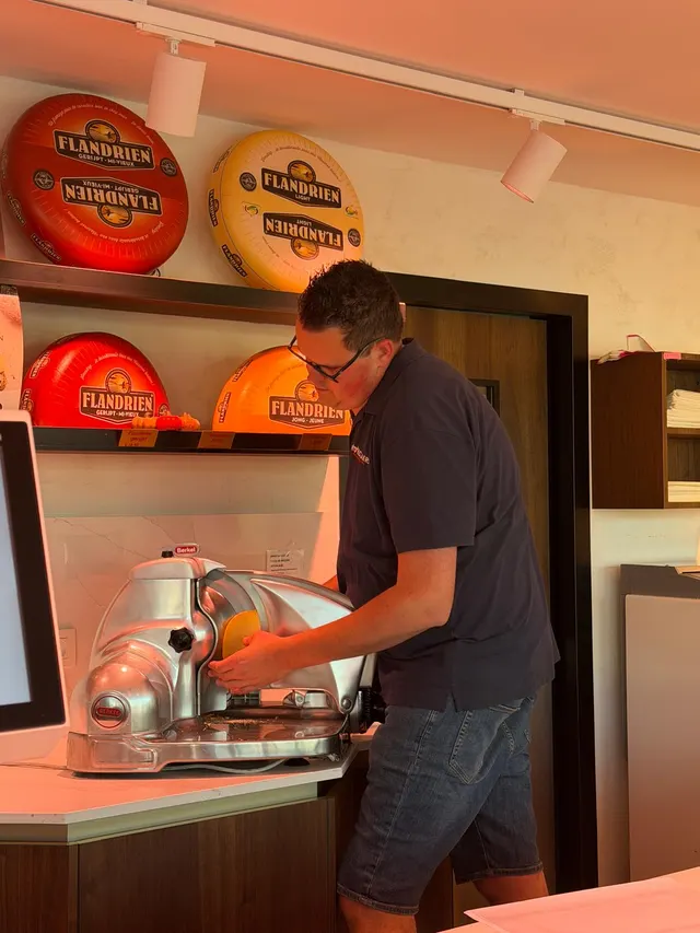 Een medewerker snijdt kaas aan de snijmachine in de winkel