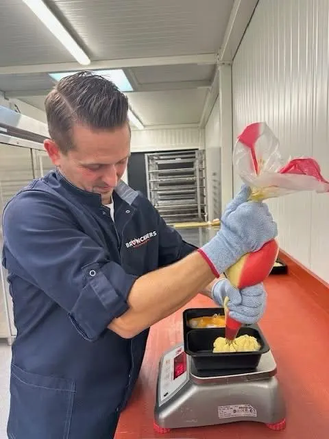 Aaron, de derde generatie, spuit aardappelpuree in een bakje in het atelier