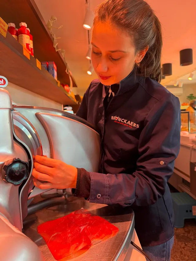 Een medewerker snijdt vleeswaren aan de snijmachine