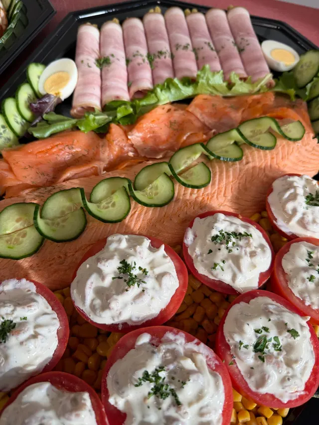 Koude schotel met gerookte zalm, komkommer en tomaat gevuld met garnalen
